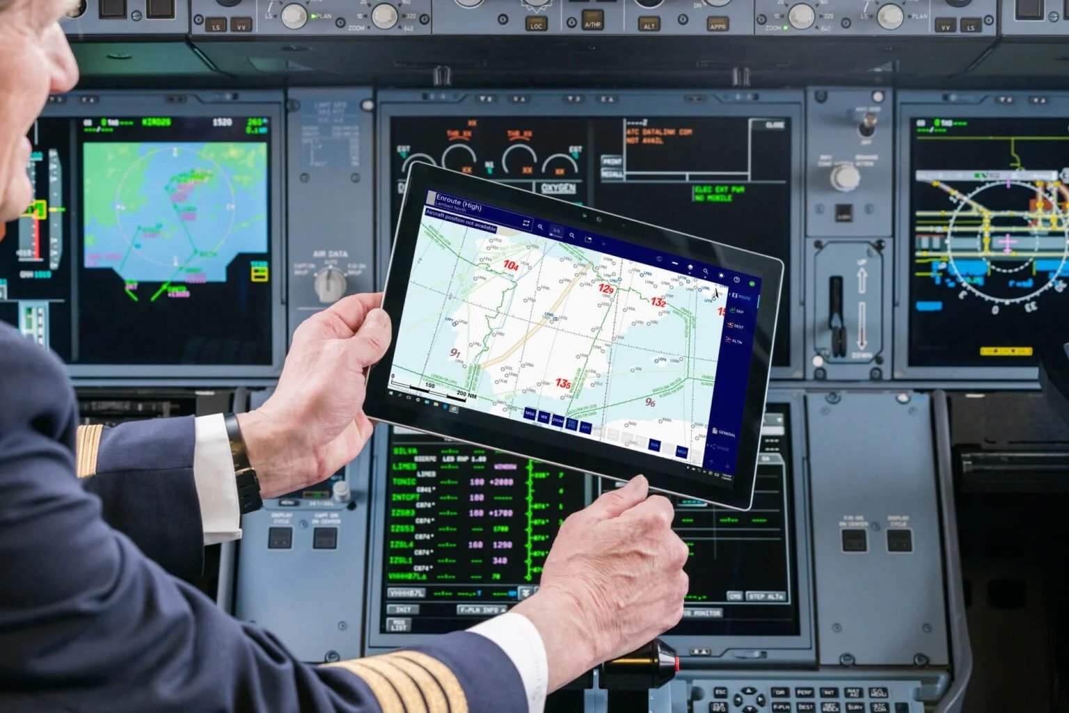 Captain in the cockpit checking overflight and landing clearances on an enroute chart tablet