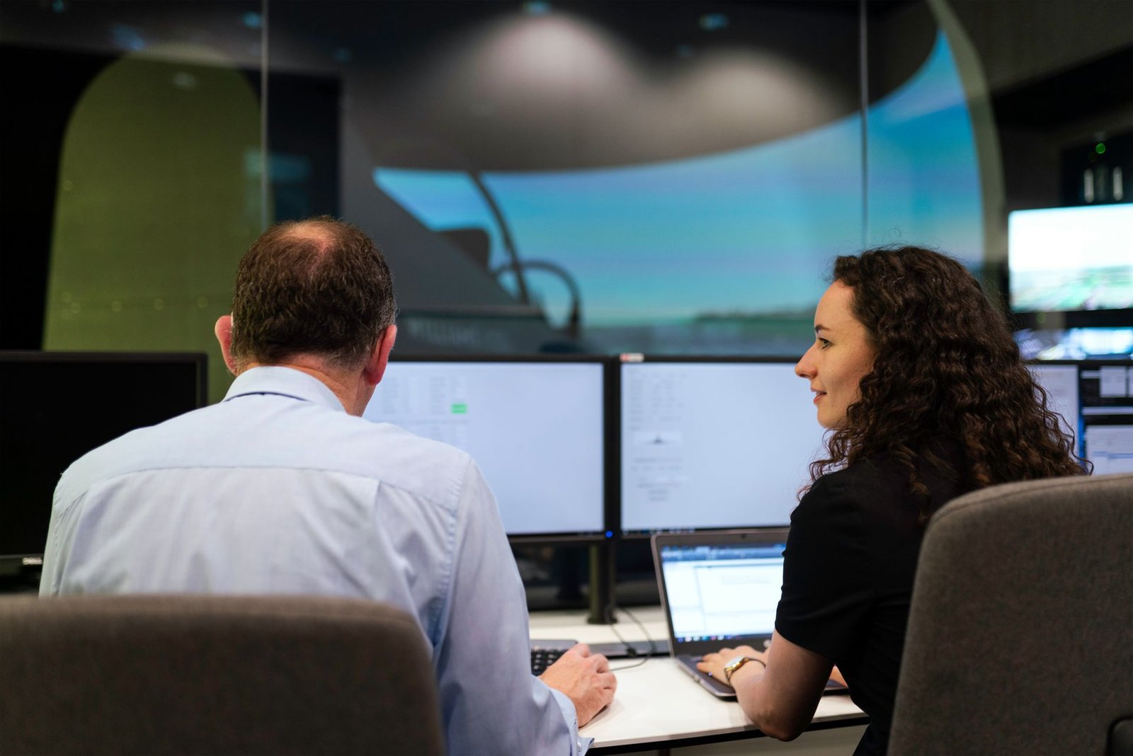 Two operations specialists reviewing flight data at a control center workstation